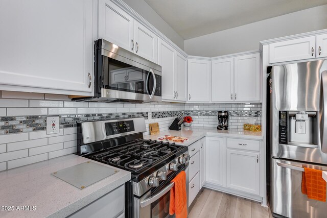 kitchen featuring white cabinetry, tasteful backsplash, stainless steel appliances, and light wood-style flooring