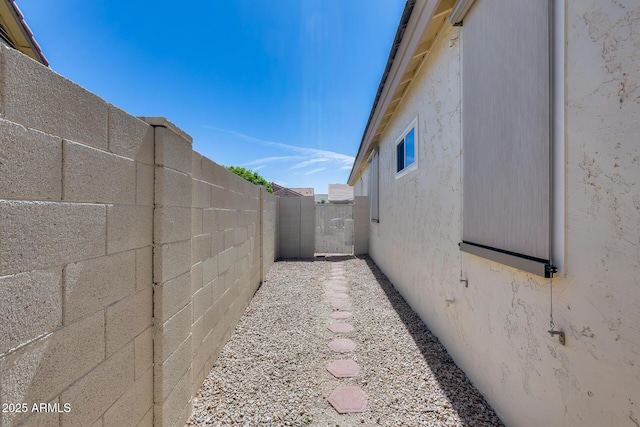 view of side of home featuring a fenced backyard and stucco siding