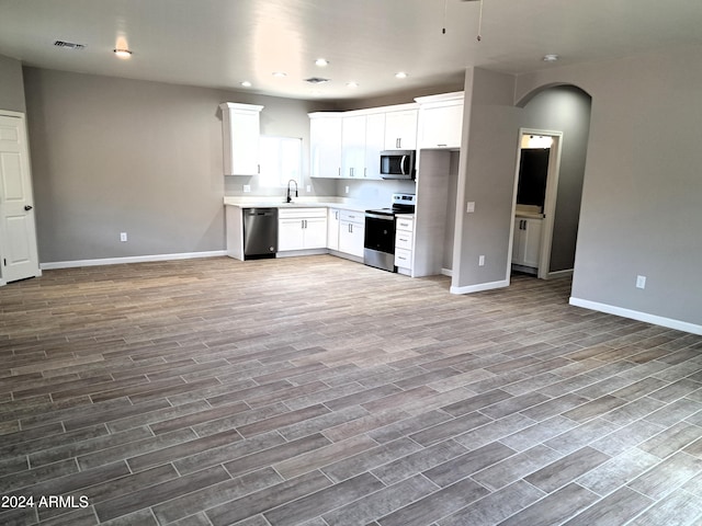 kitchen with appliances with stainless steel finishes, sink, wood-type flooring, and white cabinetry