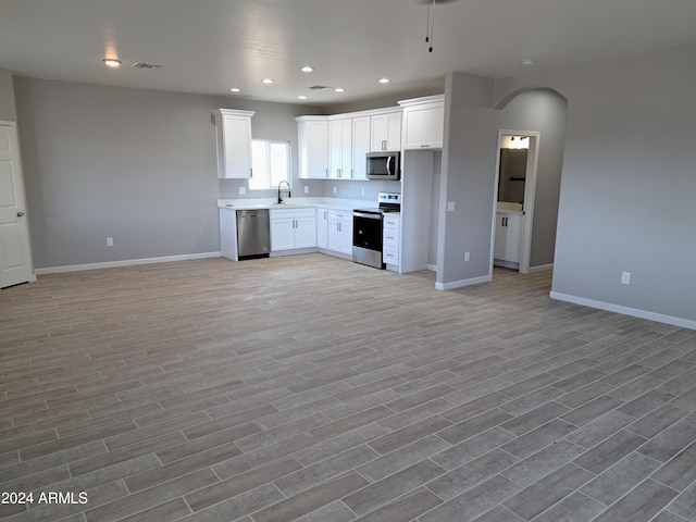 kitchen with light wood-type flooring, sink, stainless steel appliances, and white cabinetry