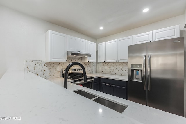 kitchen with stainless steel appliances, light stone counters, sink, white cabinetry, and backsplash