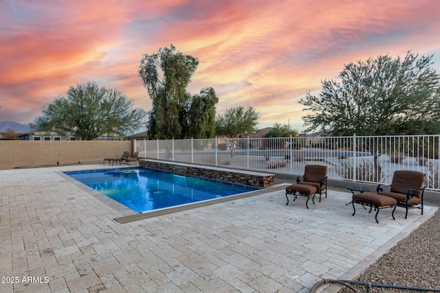 pool at dusk featuring a patio area