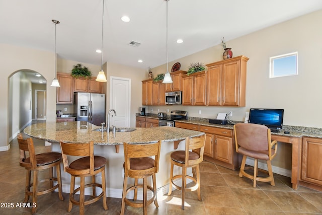 kitchen with pendant lighting, appliances with stainless steel finishes, sink, a center island with sink, and a breakfast bar area