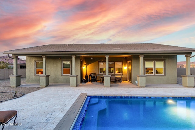 back house at dusk featuring a patio area