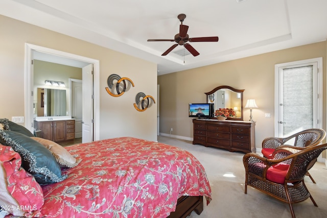 bedroom with connected bathroom, ceiling fan, a raised ceiling, and multiple windows