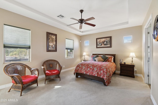 bedroom featuring light carpet, a tray ceiling, and ceiling fan