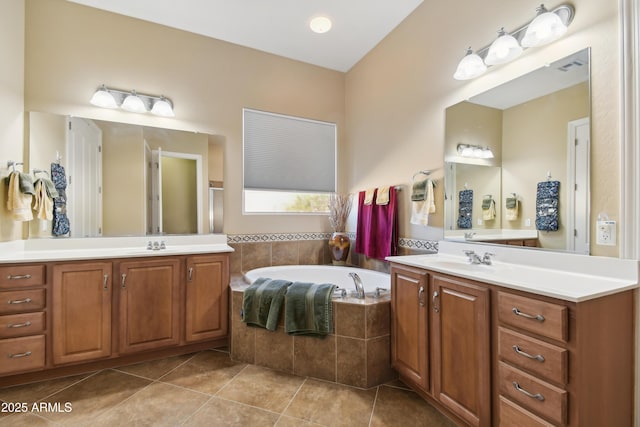 bathroom featuring tile patterned flooring, a relaxing tiled tub, and vanity