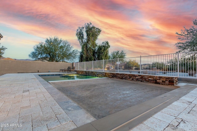 pool at dusk featuring a patio