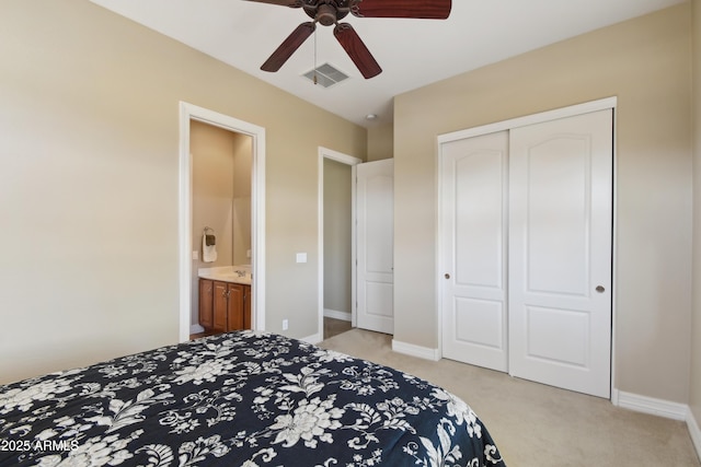 carpeted bedroom featuring a closet, ensuite bath, and ceiling fan