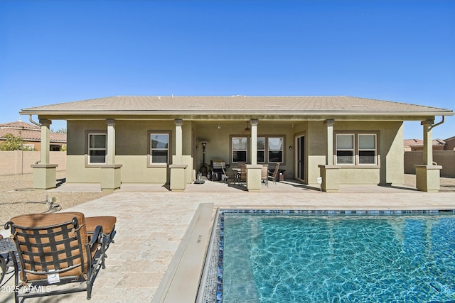 rear view of house with a fenced in pool and a patio area