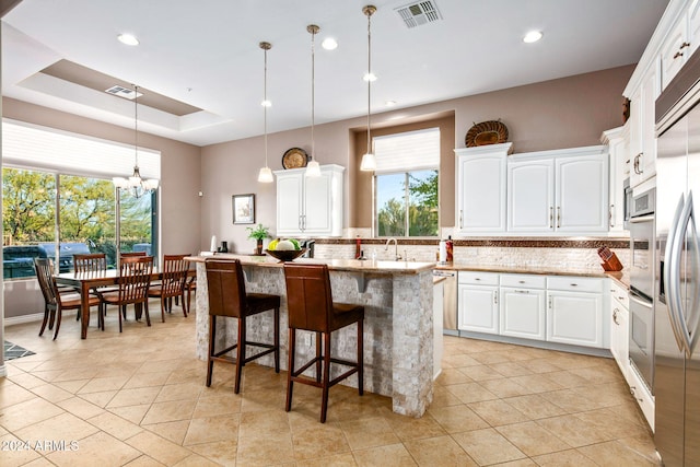 kitchen with white cabinets, decorative backsplash, pendant lighting, and a kitchen island