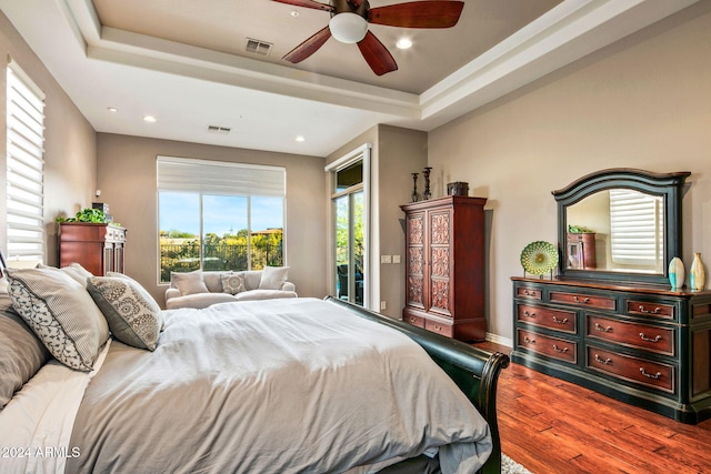 bedroom featuring a tray ceiling, ceiling fan, and wood-type flooring