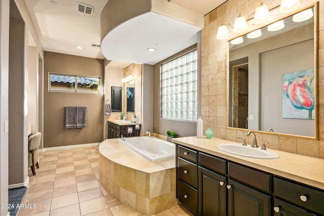 bathroom with tile patterned floors, vanity, and a relaxing tiled tub