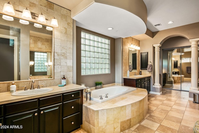 bathroom with vanity, ornate columns, and tiled bath