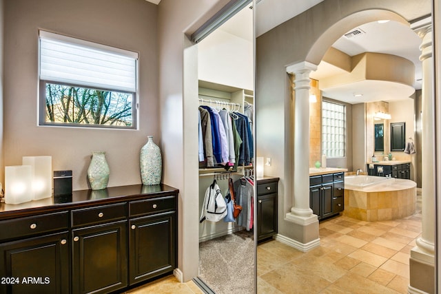 bathroom with vanity, decorative columns, a wealth of natural light, and tiled tub