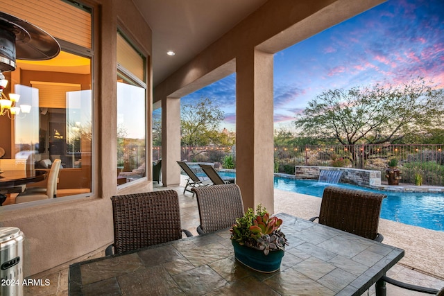 patio terrace at dusk featuring pool water feature and a pool with hot tub