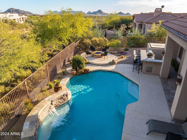 view of pool with area for grilling, a bar, a fire pit, a patio area, and a mountain view