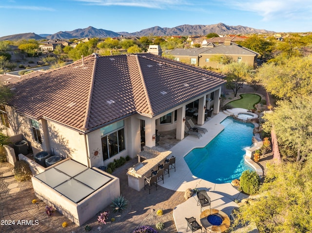 view of swimming pool featuring a mountain view, a patio area, exterior bar, and an in ground hot tub