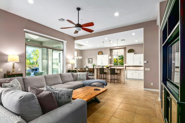 living room featuring light tile patterned floors and ceiling fan with notable chandelier