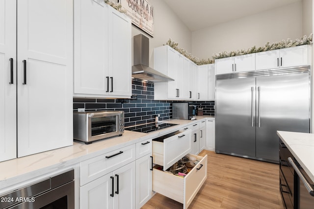 kitchen featuring backsplash, white cabinets, built in appliances, and light stone counters