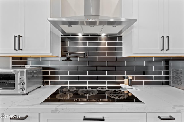 kitchen featuring decorative backsplash, light stone counters, white cabinetry, and exhaust hood