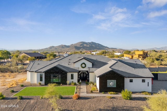 view of front of home with a mountain view and a front lawn