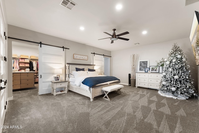 carpeted bedroom with connected bathroom, ceiling fan, and a barn door