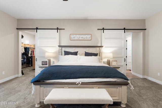 carpeted bedroom featuring a closet, a walk in closet, and a barn door