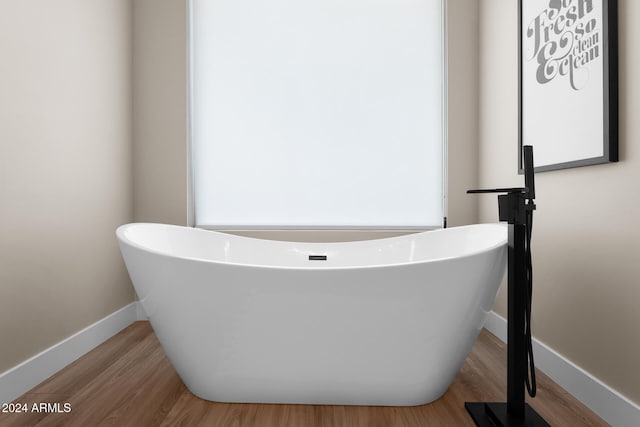 bathroom with wood-type flooring and a tub to relax in