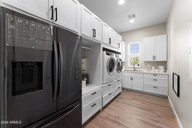 laundry area featuring sink, light hardwood / wood-style floors, and washing machine and dryer