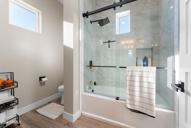 bathroom with wood-type flooring, enclosed tub / shower combo, and toilet