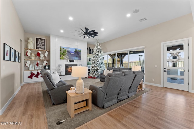 living room with ceiling fan, light hardwood / wood-style floors, and a fireplace