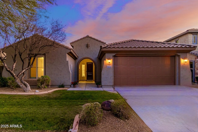 mediterranean / spanish house featuring a garage, stucco siding, driveway, and a front yard