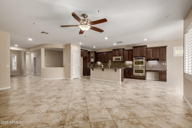 kitchen with double oven, dark countertops, open floor plan, and a kitchen breakfast bar