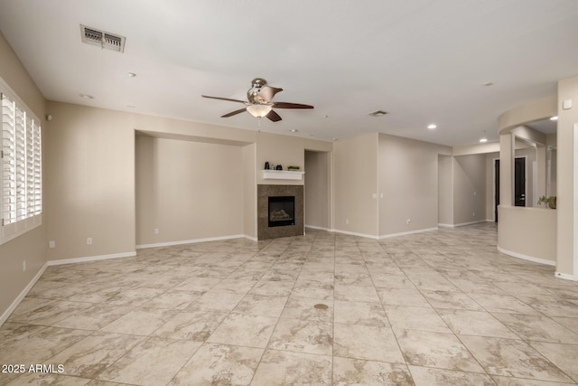 unfurnished living room with ceiling fan, a fireplace, visible vents, and baseboards