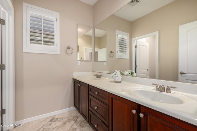 bathroom with double vanity, a sink, visible vents, and baseboards