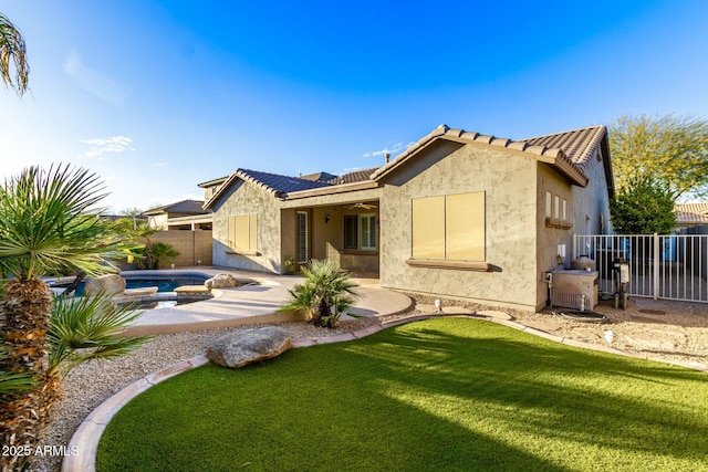 back of property with a fenced backyard, a tile roof, a lawn, stucco siding, and a patio area