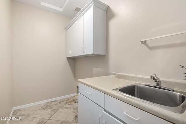 laundry area with attic access, a sink, visible vents, and baseboards