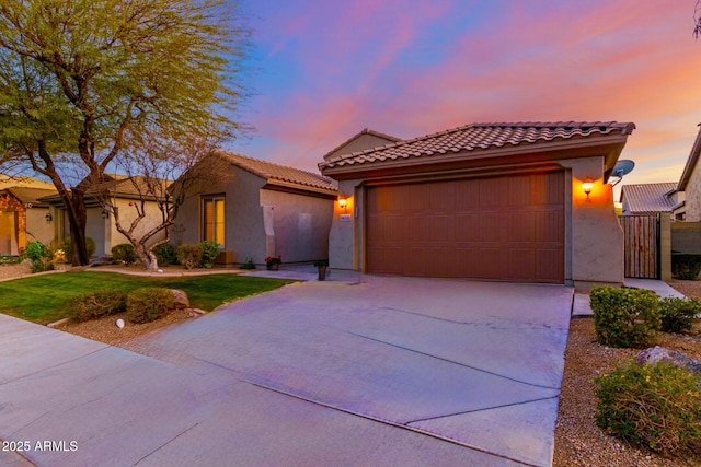 view of front of property featuring a garage, a tile roof, driveway, and stucco siding