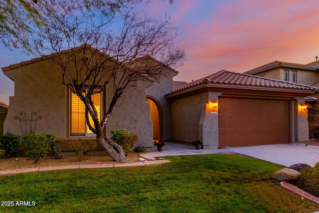 mediterranean / spanish-style house with stucco siding, a lawn, a garage, driveway, and a tiled roof