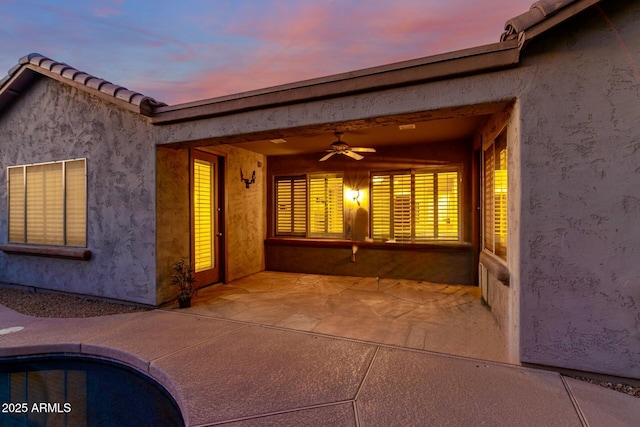 exterior space with ceiling fan, a patio, a tiled roof, and stucco siding