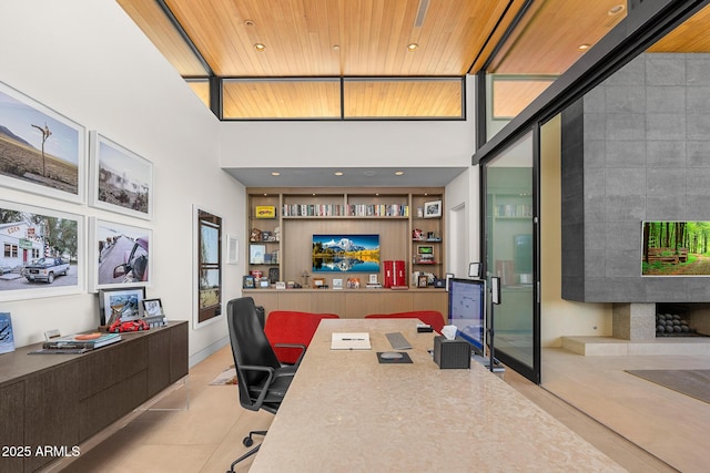 office space with light tile patterned floors, wood ceiling, built in features, and a towering ceiling