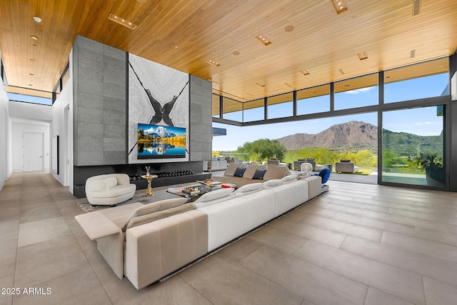 living room featuring a high ceiling, floor to ceiling windows, a mountain view, and wooden ceiling