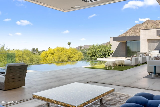 view of patio / terrace featuring an outdoor living space, a water and mountain view, and a grill