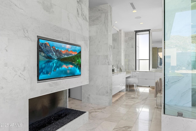 bathroom with walk in shower, vanity, and tile walls