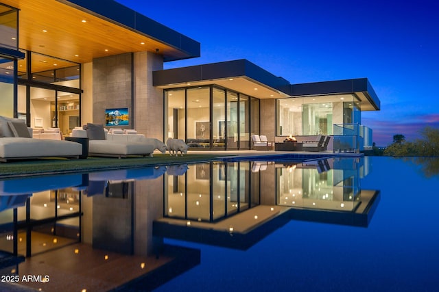 pool at dusk featuring an outdoor living space with a fire pit and a patio area