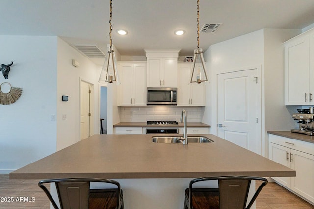 kitchen with a kitchen breakfast bar, decorative backsplash, a kitchen island with sink, and sink