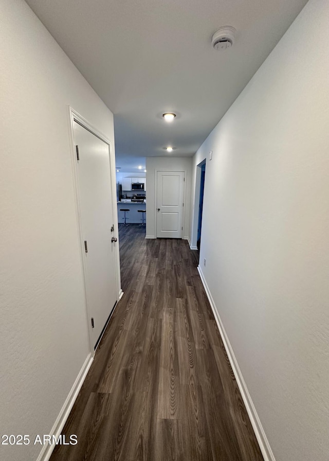 hallway with baseboards and dark wood-style floors