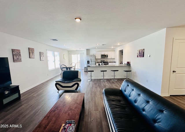 living area with dark wood-style flooring, baseboards, and recessed lighting