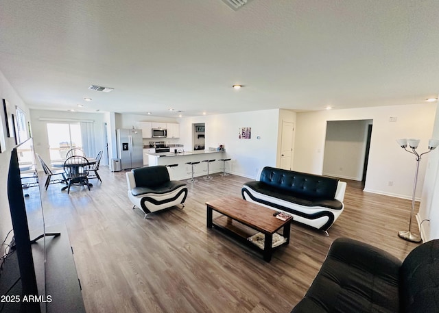 living room with wood finished floors, baseboards, and recessed lighting